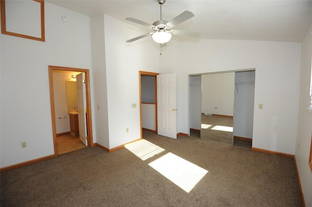 unfurnished bedroom featuring ceiling fan, high vaulted ceiling, connected bathroom, dark carpet, and a closet