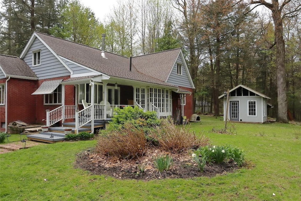 exterior space featuring an outdoor structure, a shingled roof, a yard, and brick siding