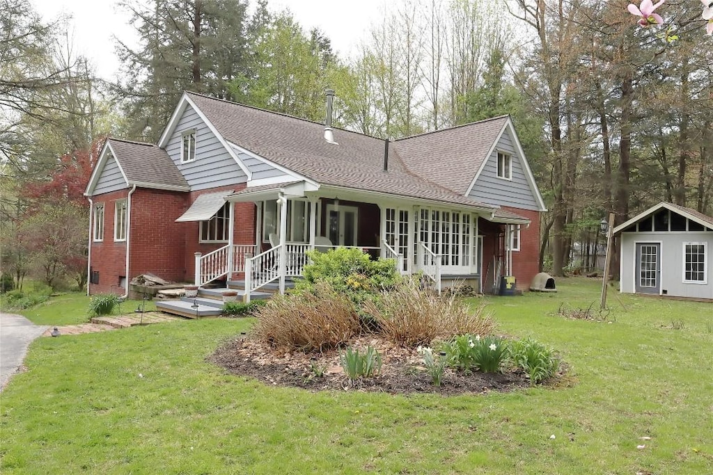 single story home with a shingled roof, a front lawn, and brick siding
