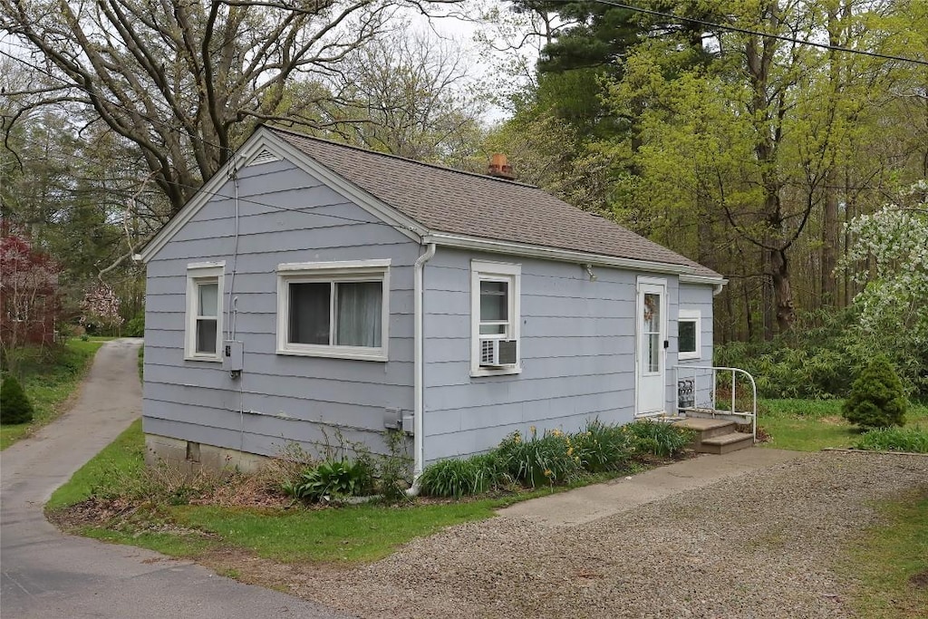 view of side of home with roof with shingles and a chimney