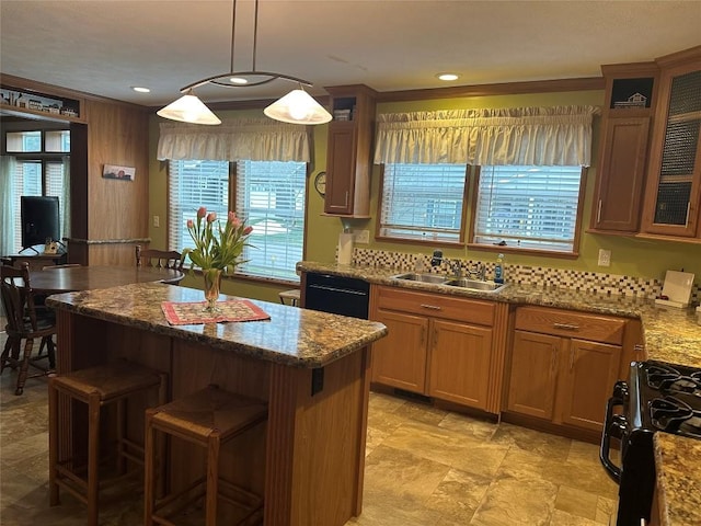 kitchen featuring light stone countertops, sink, pendant lighting, a kitchen bar, and black appliances