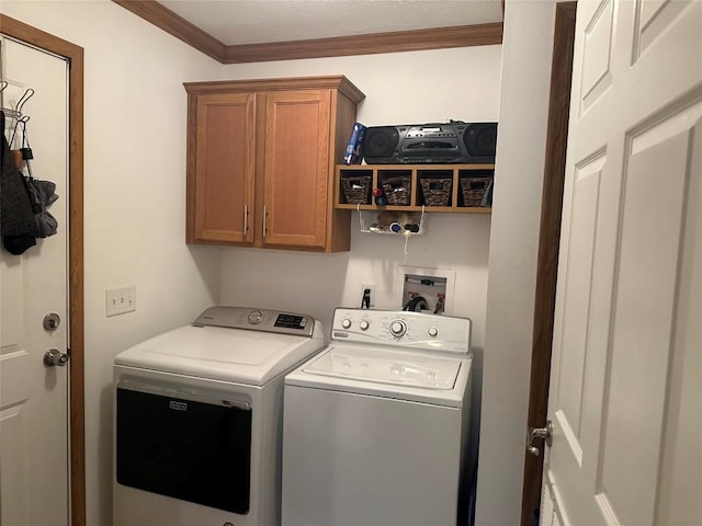 washroom featuring washing machine and dryer, crown molding, and cabinets