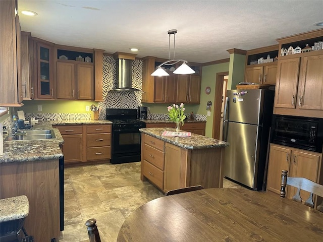 kitchen with gas stove, wall chimney range hood, a center island, stainless steel refrigerator, and hanging light fixtures