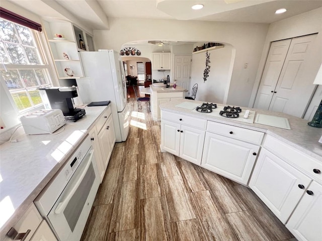 kitchen featuring white cabinets, plenty of natural light, light wood-type flooring, and white appliances