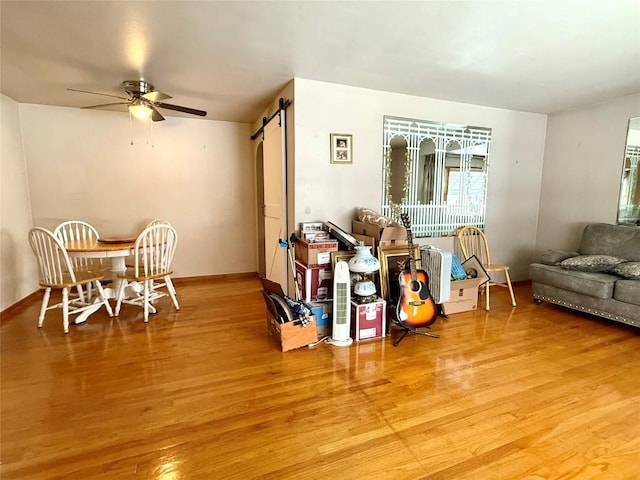 living room featuring a barn door, ceiling fan, and hardwood / wood-style floors