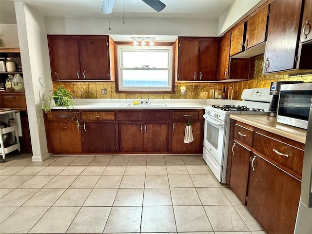 kitchen featuring light tile patterned flooring, backsplash, gas range gas stove, and sink