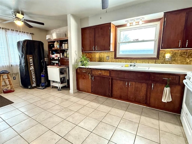 kitchen featuring white range oven, light tile patterned floors, tasteful backsplash, and sink