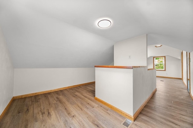 bonus room with baseboards, light wood finished floors, and vaulted ceiling