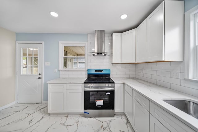 kitchen featuring wall chimney exhaust hood, stainless steel electric range, light marble finish flooring, tasteful backsplash, and recessed lighting