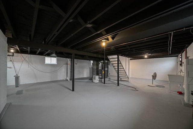 below grade area with stairs, heating unit, and a sink