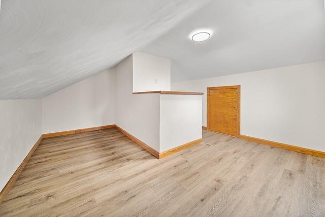 bonus room featuring vaulted ceiling, light wood finished floors, and baseboards