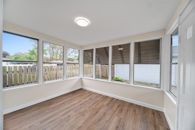unfurnished sunroom with baseboards and wood finished floors