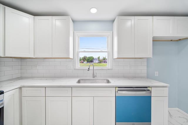 kitchen featuring dishwashing machine, a sink, and white cabinets