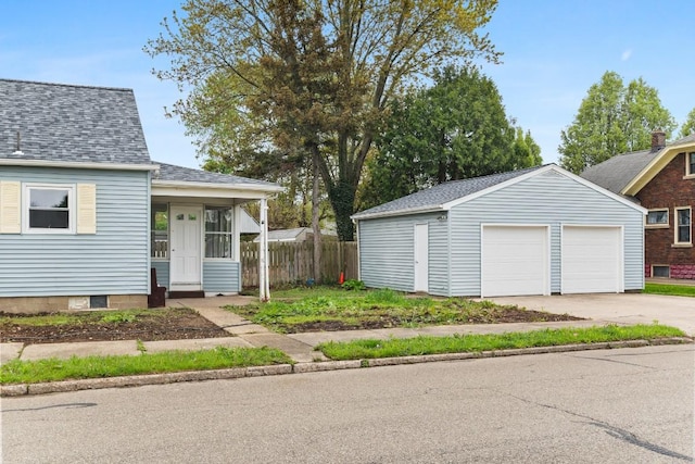 view of front of property with an outbuilding, fence, roof with shingles, and a detached garage