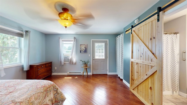 969 Lewis Way, Girard, PA 16417 - bedroom featuring a barn door, a baseboard heating unit, multiple windows, and wood finished floors