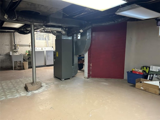 basement with washing machine and dryer, sink, and heating unit