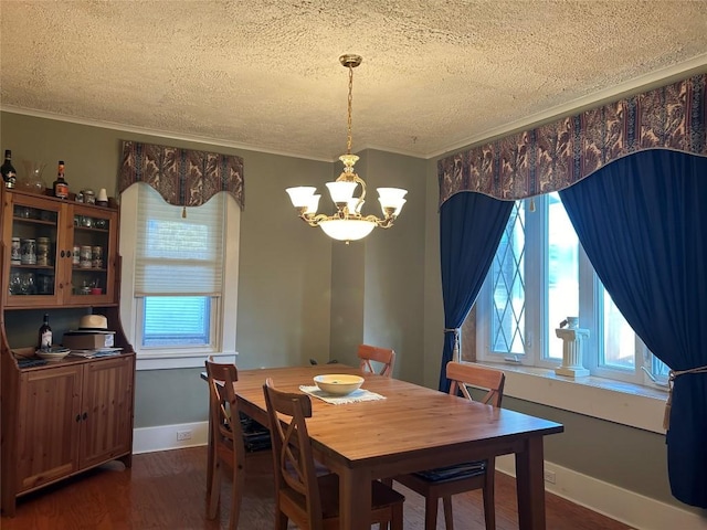 dining room with dark hardwood / wood-style floors, ornamental molding, a textured ceiling, and a chandelier