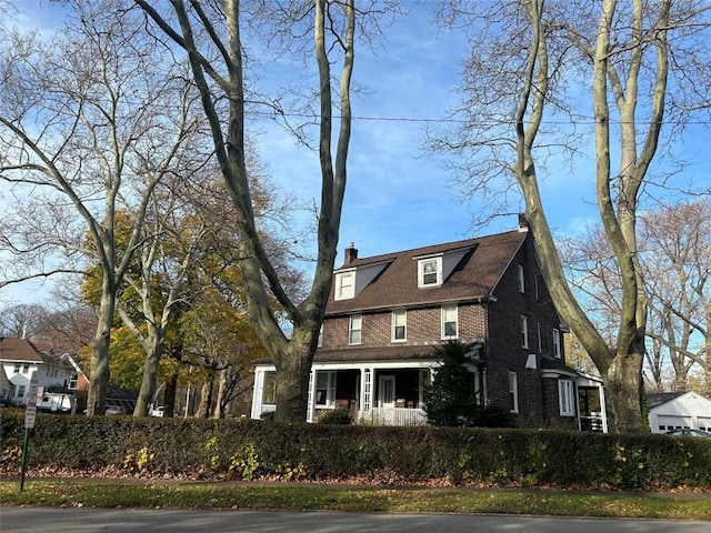 view of front facade with brick siding and a chimney