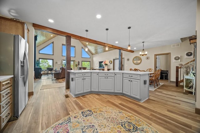 kitchen featuring beam ceiling, a center island, stainless steel fridge, decorative light fixtures, and light wood-type flooring