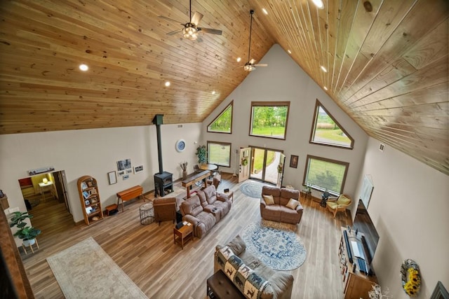 living room featuring light hardwood / wood-style floors, a wood stove, high vaulted ceiling, and wooden ceiling