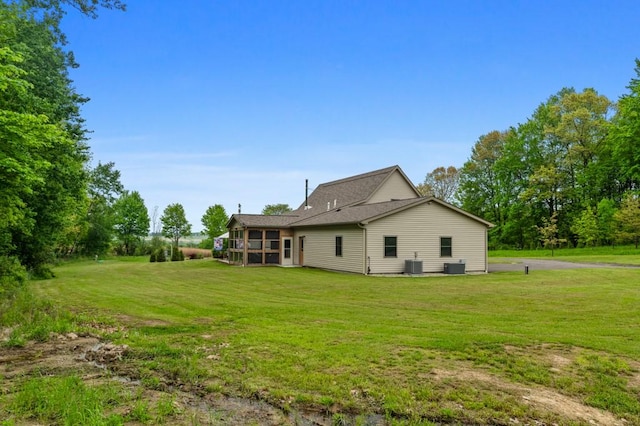 rear view of house featuring a lawn and cooling unit