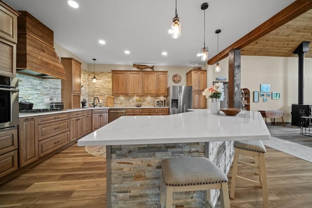 kitchen with appliances with stainless steel finishes, a kitchen breakfast bar, tasteful backsplash, a wood stove, and hanging light fixtures