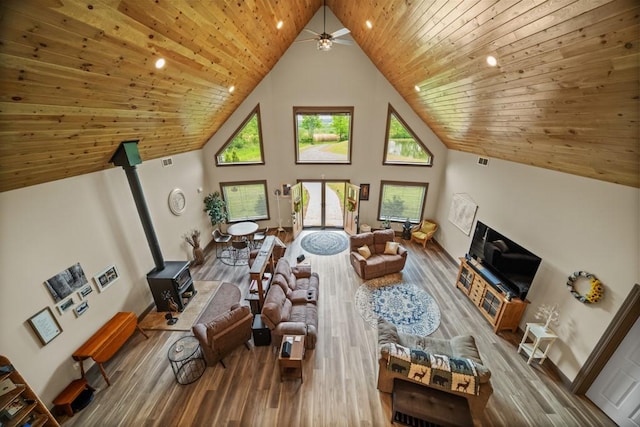 living room featuring wood-type flooring, wooden ceiling, high vaulted ceiling, and a wood stove