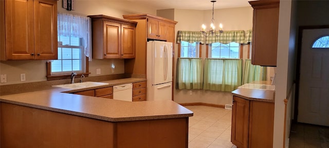 kitchen featuring pendant lighting, white appliances, sink, kitchen peninsula, and a chandelier