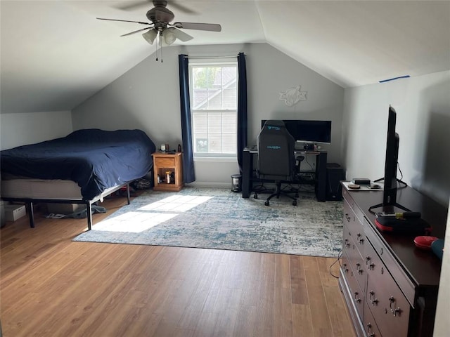 bedroom with vaulted ceiling, wood finished floors, an office area, and ceiling fan