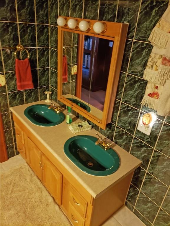 bathroom featuring tile patterned flooring, vanity, and tile walls