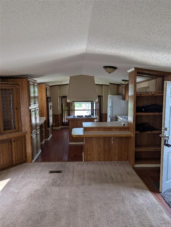 5005 Zuck Rd Unit 21, Erie, PA 16506 - kitchen with a textured ceiling, freestanding refrigerator, brown cabinets, dark carpet, and a peninsula