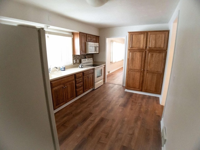 kitchen with backsplash, dark hardwood / wood-style floors, and white appliances