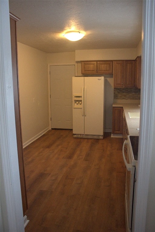 kitchen featuring backsplash, white appliances, dark hardwood / wood-style flooring, and sink