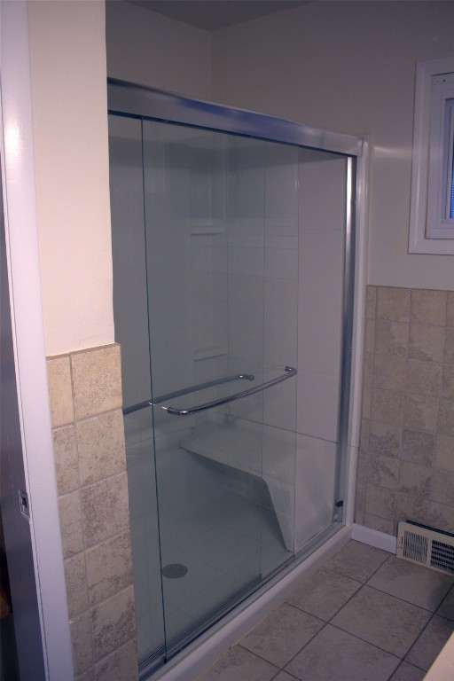 bathroom featuring tile walls, a shower with door, and tile patterned flooring