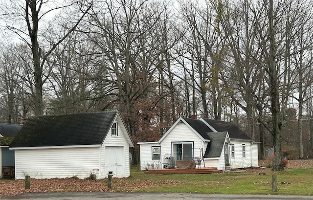 view of front facade featuring an outbuilding, a deck, and a front yard