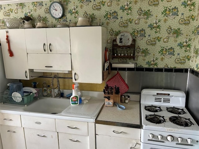 12656 Comstock St, Conneaut Lake, PA 16316 - kitchen with white range with gas cooktop, wallpapered walls, white cabinets, and light countertops