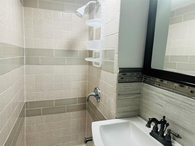 bathroom featuring tiled shower and sink