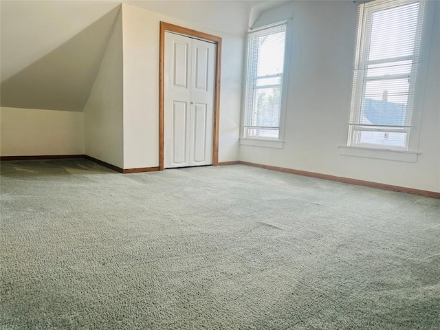 bonus room with lofted ceiling and light carpet