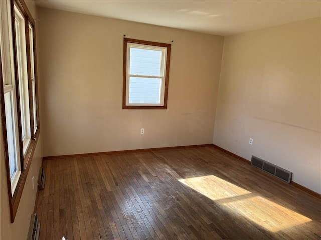 spare room with visible vents, baseboards, and hardwood / wood-style flooring