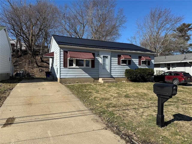 view of front of house featuring entry steps, metal roof, and a front yard