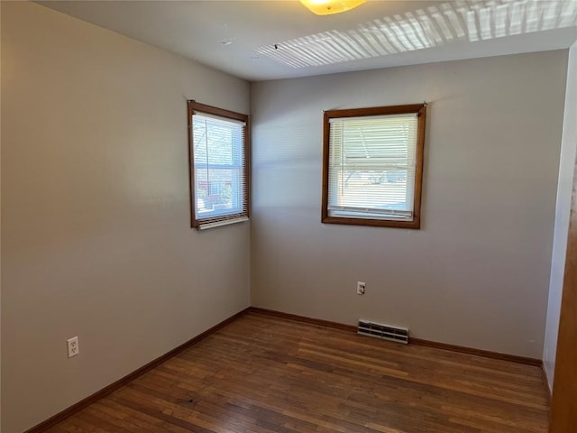 spare room with visible vents, baseboards, and hardwood / wood-style floors