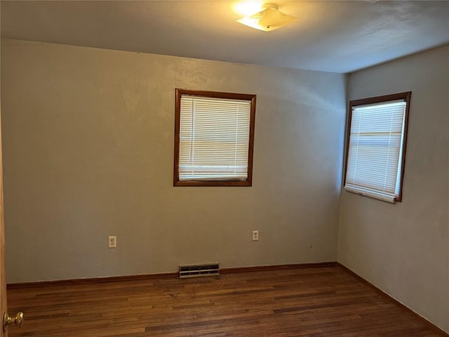 empty room with visible vents, baseboards, and wood finished floors