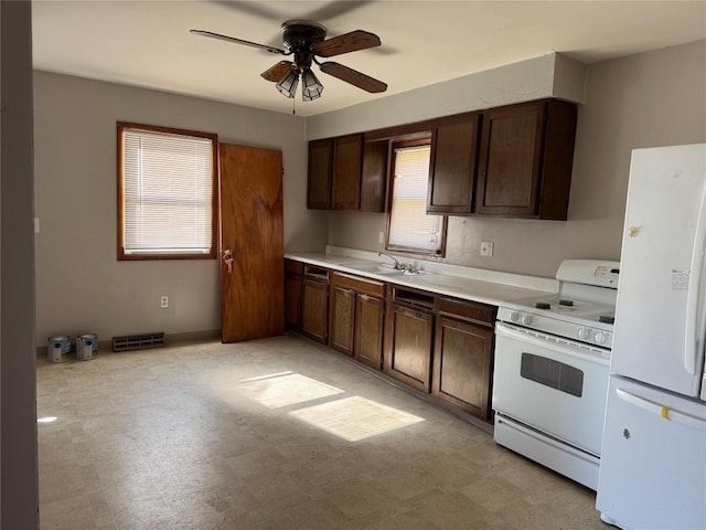 kitchen with white appliances, light floors, visible vents, and a sink