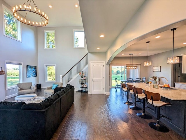 living room featuring a chandelier, a towering ceiling, dark hardwood / wood-style floors, and sink