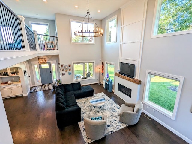 living room featuring a high ceiling, dark hardwood / wood-style flooring, and a healthy amount of sunlight