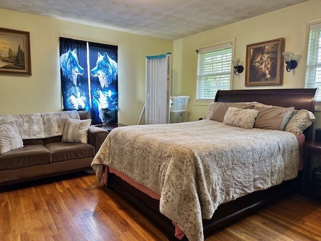 bedroom featuring a textured ceiling, multiple windows, and hardwood / wood-style floors
