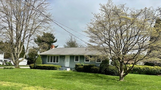 view of front facade with a front lawn and a chimney