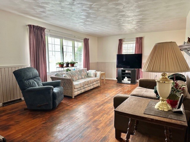living room featuring a textured ceiling, wainscoting, radiator heating unit, and hardwood / wood-style flooring