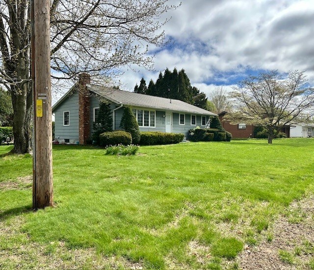 back of property featuring a lawn and a chimney