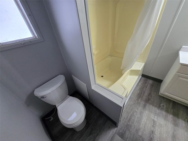 full bathroom featuring hardwood / wood-style flooring, toilet, vanity, and shower / tub combo